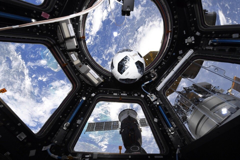 bola sepak melayang di depan jendela multi-panel di angkasa dengan bumi di belakangnya