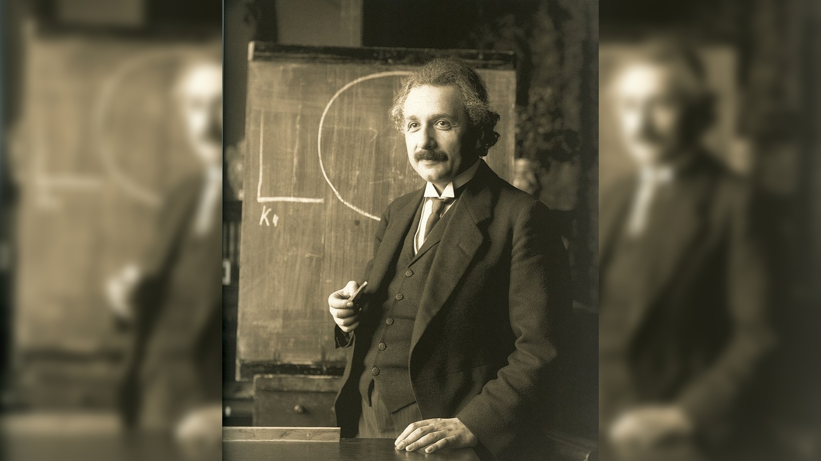Albert Einstein berdiri di samping papan tulis
