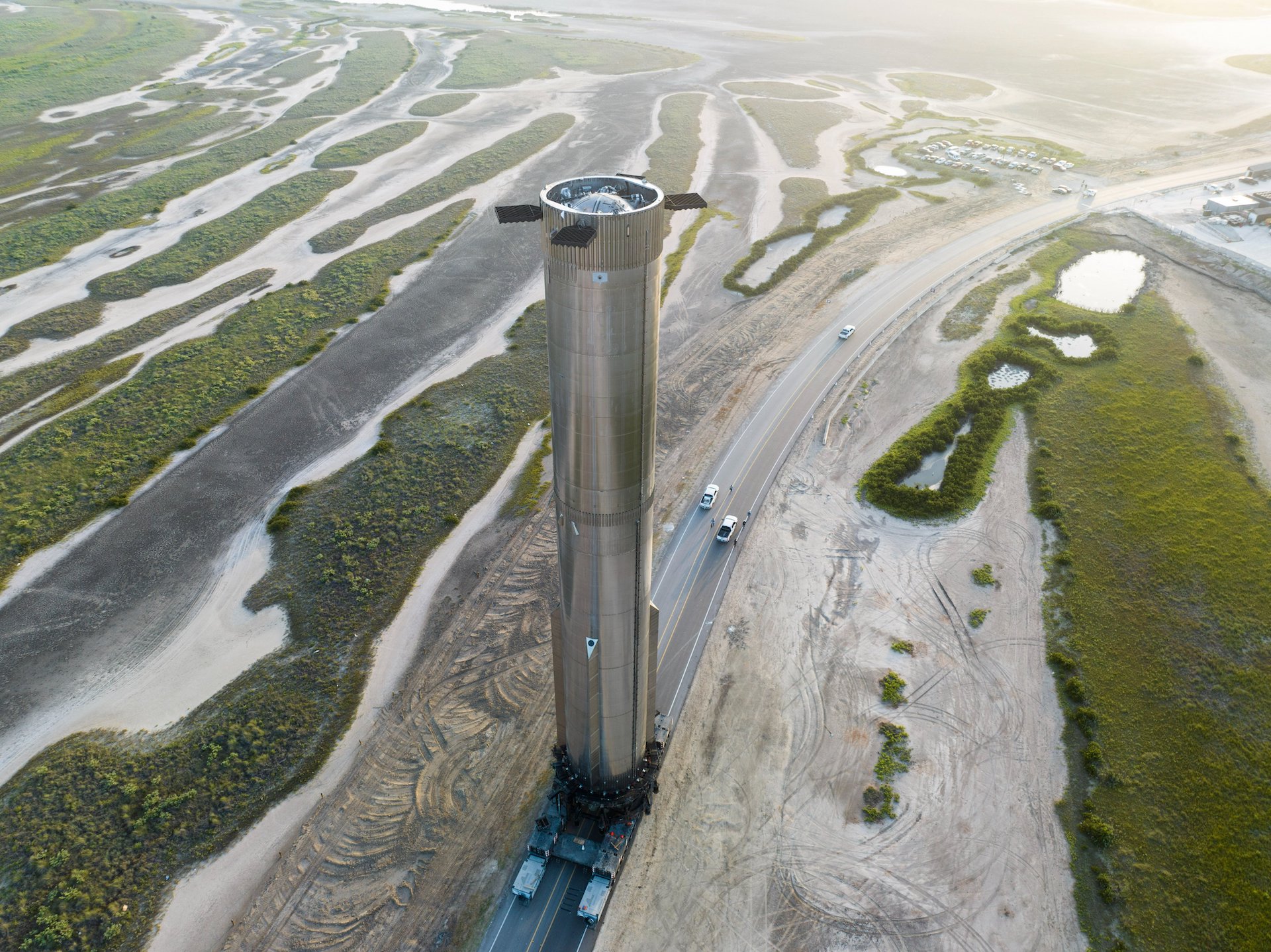 Menara penguat super berat yang sangat tinggi di atas lanskap Texas yang datar saat diangkut ke landasan peluncuran.