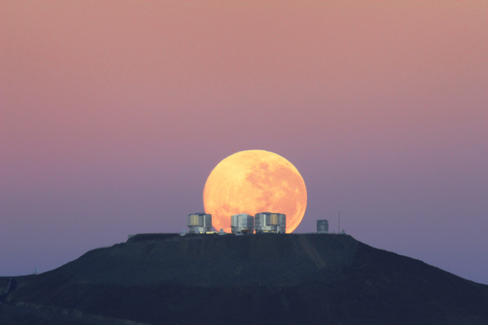 bulan tampak besar di atas puncak gunung