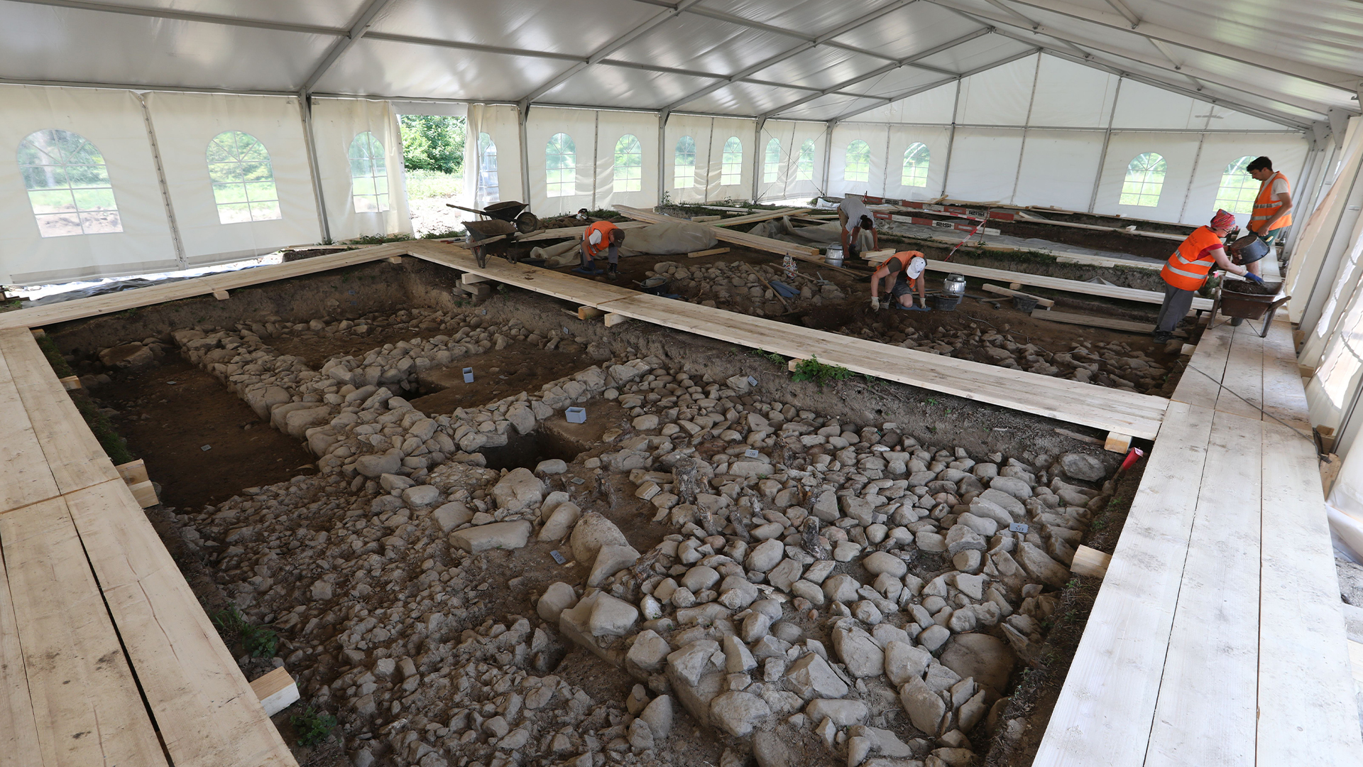 Menggali bagian dinding terbuka di situs arkeologi Cham-Äbnetwald di bawah tenda.