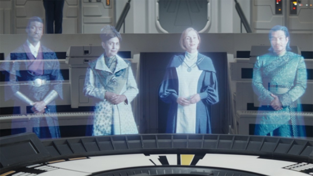 Cuplikan dari serial TV Star Wars Ahsoka, season 1, episode 3. Mon Mothma dan politisi New Republic lainnya.  Semuanya adalah hologram berwarna biru di sekeliling meja.