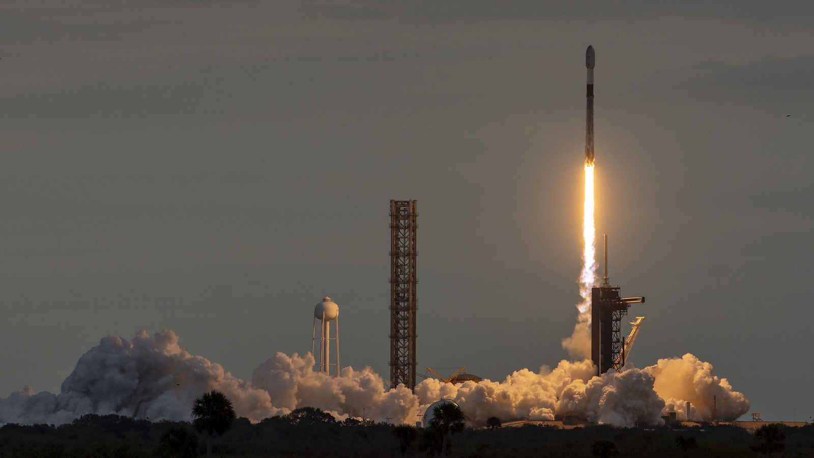 roket spacex falcon 9 hitam-putih diluncurkan ke langit kelabu