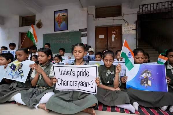 Anak-anak muda yang duduk di atas permadani di ruang kelas memegang bendera dan tanda bacaan
