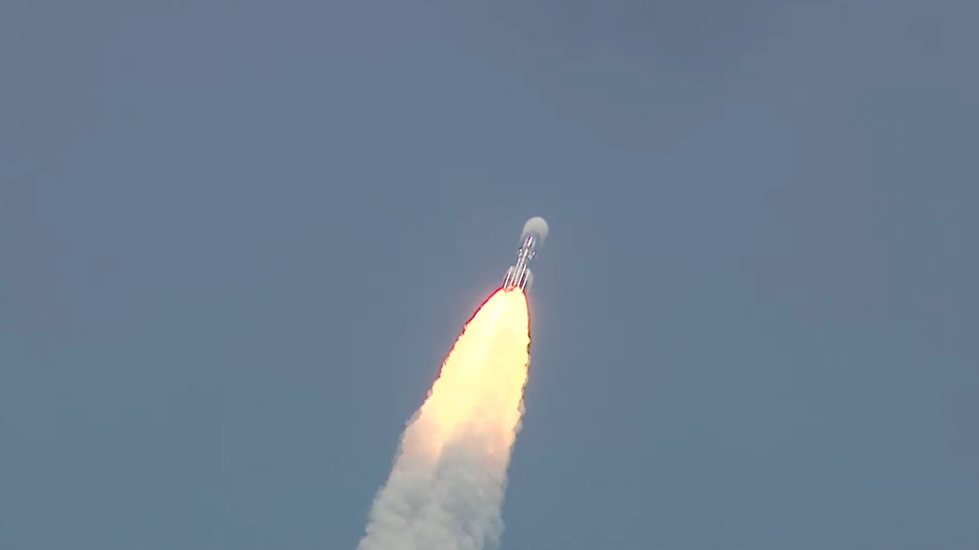 sebuah roket naik ke langit biru di atas pilar api berbentuk kerucut.